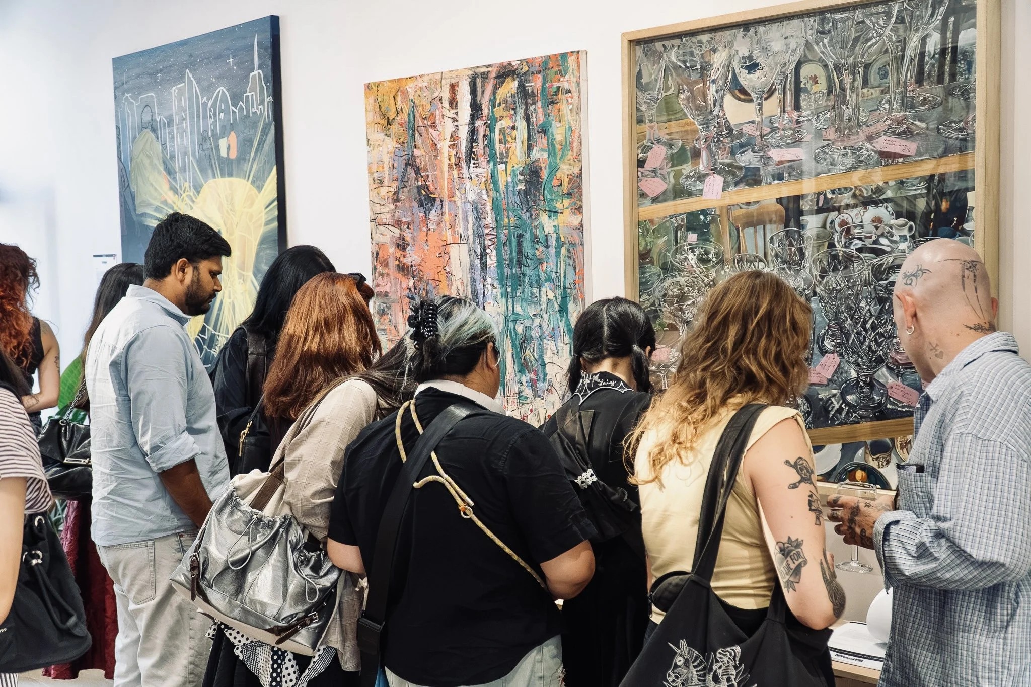 Visitors viewing several artworks on a white gallery wall